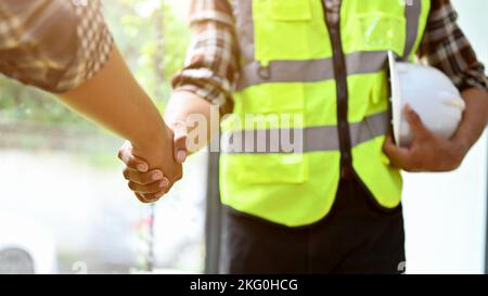 Professioneller asiatischer Ingenieur, der nach dem Meeting mit dem männlichen Bauleiter die Hände schüttelt. Teamwork-Konzept, freigeschnittenes Bild Stockfoto