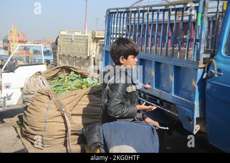 Ismalabad, Pakistan. 20.. November 2022. Afghanische Flüchtlingsjungen arbeiten auf einem Gemüsemarkt, um ihren Familien in Islamabad ihren Lebensunterhalt zu verdienen. Die in ihrer Freizeit gerne spielen. Tausende von Kindern arbeiten in Pakistan in Kinderarbeit. Beamte und Vertreter der pakistanischen Regierung sagten anlässlich des Internationalen Kindertages, dass die Regierung den Rechten der Kinder Vorrang einräumt. (Bild: © Raja Imran/Pacific Press via ZUMA Press Wire) Stockfoto