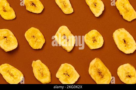 Eine Draufsicht auf eine gelbe Bananenspäne auf braunem Hintergrund Stockfoto