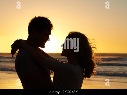 Du vervollständigst mich. Romantische Aufnahme eines Paares, das sich beim Sonnenuntergang am Strand in die Augen schaut. Stockfoto