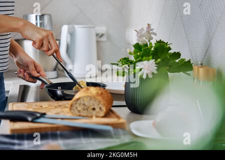Prozess der Frau beim Kochen Frühstück in der Küche. Weibliche Hände bereiten Omelett in der Pfanne mit Induktionsherd zu Stockfoto