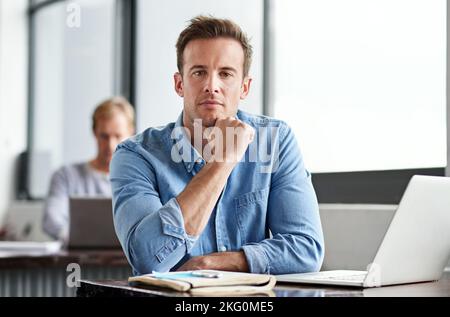 Harte Arbeit zahlt sich immer aus. Ein Mann, der in einem Büro an einem Laptop arbeitet. Stockfoto