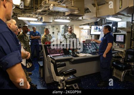 US Coast Guard Petty Officer 1. Class Steven Adams, ein Maschinentechniker an Bord des USCGC Hamilton (WMSL 753), erklärt den Technikraum während einer Tour von Hamilton in Rota, Spanien, am 20. Oktober 2022. Hamilton befindet sich im geplanten Einsatzgebiet der US Naval Forces Europe, das von der US Sixth Fleet eingesetzt wird, um die Interessen der USA, der Alliierten und der Partner zu verteidigen. Stockfoto