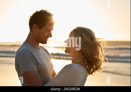 Ich liebe ihre Augen mehr als den Sonnenaufgang. Nahaufnahme eines Paares in einer warmen Umarmung am Strand. Stockfoto