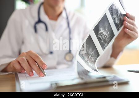 Ärztin, die sich die Beschreibung der Ultraschallaufnahmen des Patienten ansieht Stockfoto