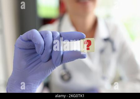 Ärztin Hand in Handschuh mit Fragezeichen Stockfoto