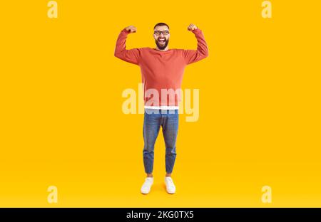 Hipster trägt einen legeren Pullover, der die Arme mit einem Lächeln und Stolz zeigt. Stockfoto