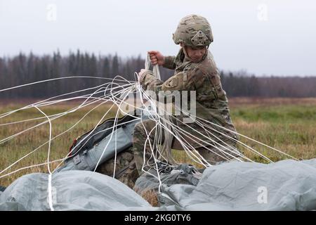 SPC der US-Armee. Hugh Parker, ein Fallschirmjäger, der dem Brigadeingenieur-Bataillon 6. (Airborne), dem Kampfteam der Infanterie-Brigade 2. (Airborne), der 11. Airborne Division (Arctic Angels), zugewiesen wurde, erholt sich nach dem Sprungtraining in der Malemute Drop Zone, Joint Base Elmendorf-Richardson, Alaska, 20. Oktober 2022, seine Fallschirme. Nach dem Flugtraining simulierten einige der Fallschirmjäger Sprungopfer für 673d medizinische Gruppenflieger, die an der Arctic Warrior Challenge 2022 teilnahmen. Die Arctic Warrior Challenge war eine szenariobasierte Feldtrainingsübung, die die 673d Medical Group A schärfen sollte Stockfoto