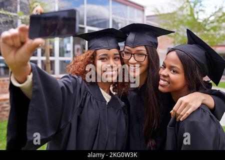 Wir haben uns fürs Leben angefreundet. Drei weibliche Absolventen, die ein Selfie am Telefon gemacht haben. Stockfoto