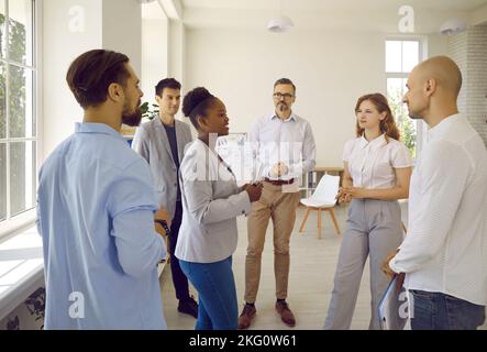 Eine Gruppe junger Wissenschaftler aus verschiedenen Ländern kommuniziert während der Pause in einem wissenschaftlichen Symposium mit einem Betreuer. Stockfoto