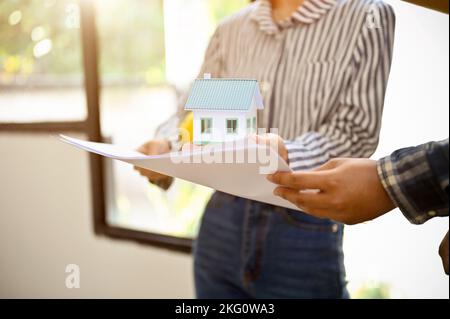 Professionelle asiatische Architektin, die den Blaudruck hält und anschaut, arbeitet mit ihrem Team im Büro Stockfoto