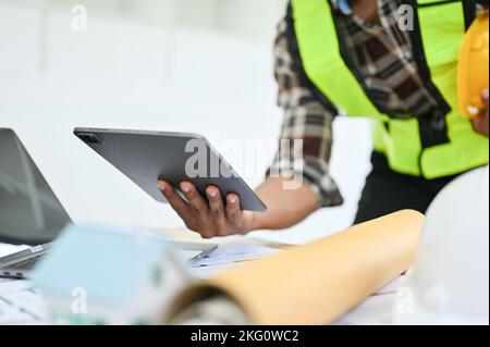 Ein asiatischer Ingenieur oder Bauarbeiter, der ein Tablet hält und in seinem Büro ein digitales Tablet verwendet Stockfoto