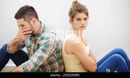 In der Konfliktzone. Ein junges Paar mit Beziehungsschwierigkeiten, das sich zurück an den Rücken lehnen muss. Stockfoto