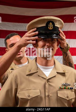 POLARIS POINT, Guam (Okt 21, 2022) Chief Electronics Technician, Nuclear Power Jacob Davis, der USS Springfield (SSN 761) zugewiesen wurde, erhält während einer Promotionszeremonie am 21. Oktober seinen Chief Petty Officer Combination Cover von Christopher Ries, dem leitenden Chief Information System Technician (Submarine). Springfield ist eines von mehreren U-Booten, die Commander, Submarine Squadron 15, zugewiesen wurden. Commander, Submarine Squadron 15, ist für die Schulung, Material- und Personalunterstützung für mehrere Schnellangriffsuntermarine der Los Angeles-Klasse verantwortlich und befindet sich am Polaris Point, Naval Base Guam. Stockfoto