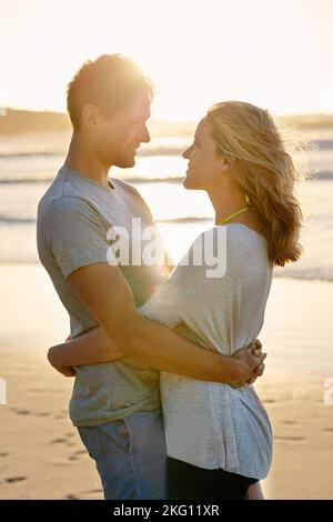 Halte mich fest und lass mich nie los. Ein Paar hält sich am Strand um die Taille. Stockfoto