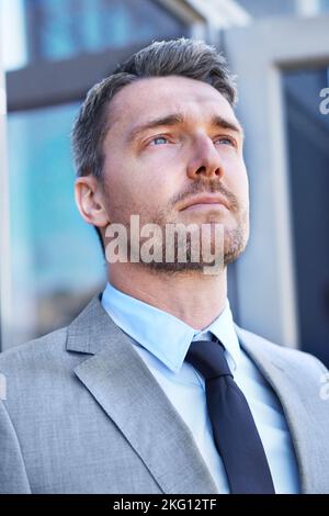 Sein Ziel ist der Erfolg. Kopf- und Schulteraufnahme eines ernsthaft aussehenden Geschäftsmannes, der draußen steht. Stockfoto