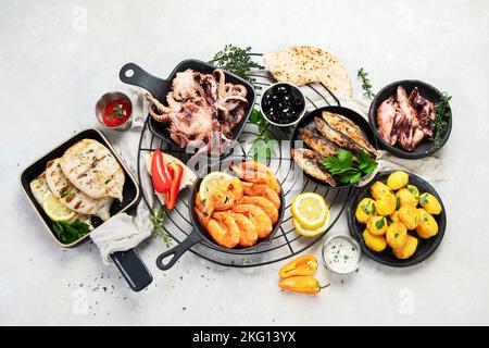 Meeresfrüchte-Platte. Gemischte köstliche Meeresfrüchte mit Gemüse auf grauem Hintergrund. Draufsicht. Stockfoto
