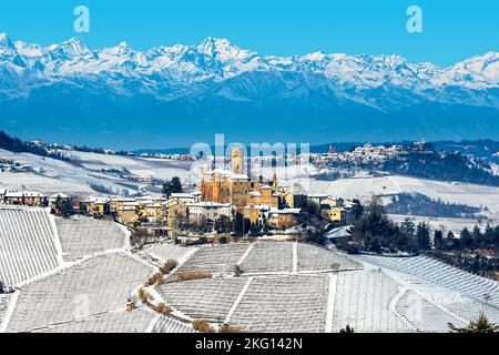 Blick auf kleine mittelalterliche Stadt auf dem mit Schnee bedeckten Hügel als Berge im Hintergrund im Winter in Piemont, Norditalien. Stockfoto