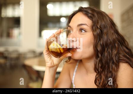 Glückliche Frau, die Limonade trinkt und in einer Bar wegschaut Stockfoto