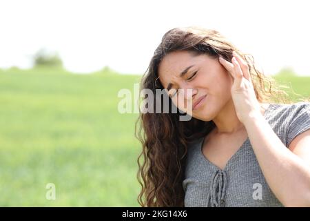 Frau, die sich auf einem Feld über Ohrenschmerzen beschwert Stockfoto