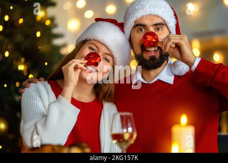 Frohe Weihnachten. Ein glückliches Paar isst zu Hause zu Abend. Feiertag und Zusammensein in der Nähe von Bäumen. Stockfoto