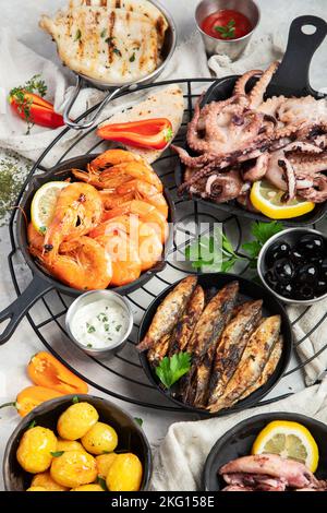 Meeresfrüchte-Platte. Gemischte köstliche Meeresfrüchte mit Gemüse auf grauem Hintergrund. Draufsicht. Stockfoto