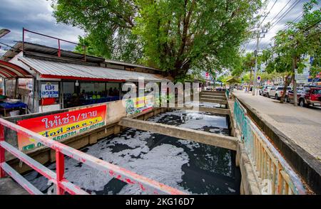 November 17 2022 - Bangkok Thailand - stark verschmutzte Kanalisation mit sehr schmutzigem Wasser, das an Restaurants vorbeiläuft, in denen Einheimische essen. Stockfoto