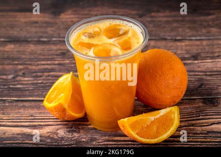 Frisch gepresster Orangensaft mit Eiswürfeln auf Holztisch Stockfoto