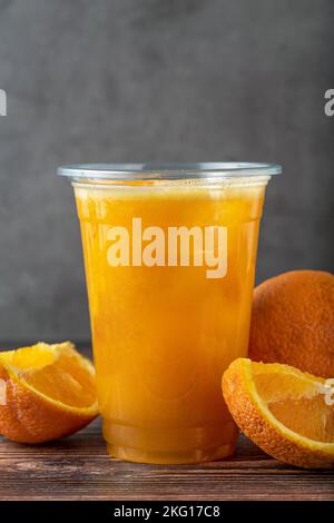 Frisch gepresster Orangensaft mit Eiswürfeln auf Holztisch Stockfoto
