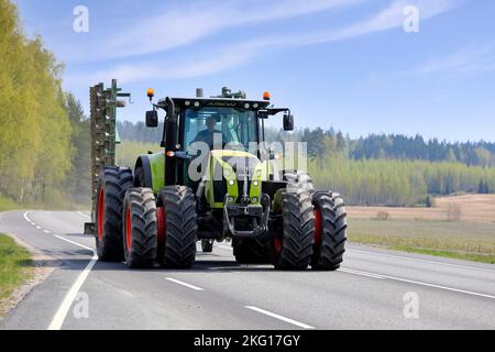 Großer grüner Claas Arion 640 Traktor mit Doppelreifen, der an einem sonnigen Maitag landwirtschaftliche Geräte auf der Straße zieht. Salo, Finnland. 13.Mai 2021. Stockfoto