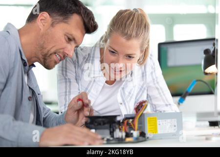 Junge Studenten der Robotik, die Roboter für Tests in der Werkstatt vorbereiten Stockfoto