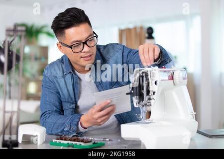 Mechaniker reparieren Industrienähmaschine in Fabrik Stockfoto