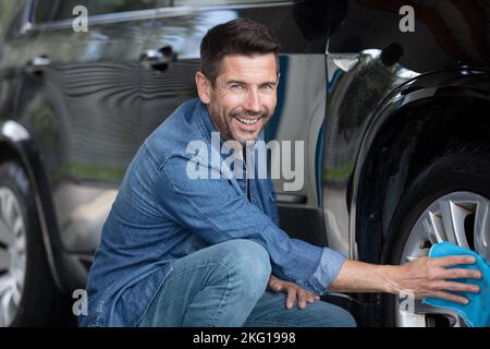 Mann, der sich um einen Autoreifen kümmert Stockfoto