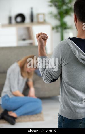 Betrunkener Mann mit Flasche, der seine Frau auf dem Boden missbraucht Stockfoto