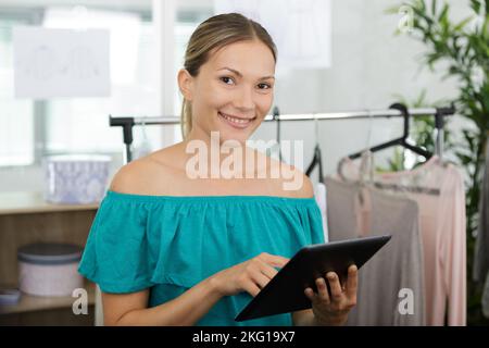 Glückliche Frau in Kleidung Shop halten Tablet Stockfoto