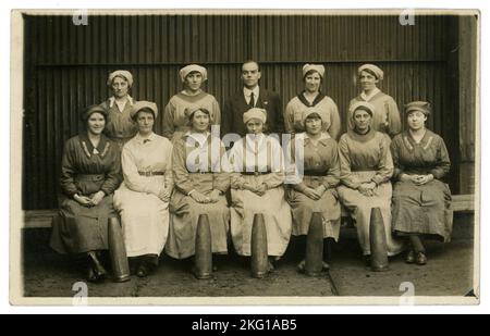 Originale Postkarte aus der WW1. Ära, vor dem Porträt von Munitions-Mädchen mit Patronenhülsen. Inspektor Far LH Side mit „war Service“-Emblem und FAR RH Side. Manager hinten. GROSSBRITANNIEN 1916-1918. Stockfoto