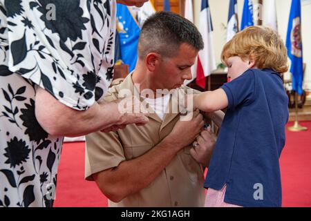 221021-N-CR158-1059 GUANTANAMO BAY, Kuba (Okt 21, 2022) der Mate Christopher Gibson von US-Navy-Chef Boatswain wird von seinem Sohn Declan während einer Chief Pinning Ceremony an Bord der Naval Station Guantanamo Bay am 21. Oktober 2022 festgehalten. Die Marinestation Guantanamo Bay ist die vorwärtsbereite, unersetzliche US-Seekraftplattform in der Karibik. Stockfoto