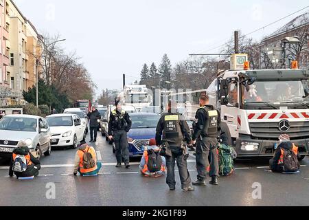 Berlin, Deutschland. 21.. November 2022. Aktivisten halten Schilder und sitzen auf der Prenzlauer Allee. Neben den Protesten für mehr Umweltschutz demonstrierten die Teilnehmer auch gegen die Verhaftung anderer Aktivisten. Einige Aktivisten hielten sich an der Straße fest. Quelle: Carsten Koall/dpa/Alamy Live News Stockfoto