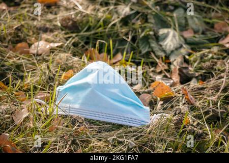 Eine blaue medizinische Maske, die auf einem Feld auf grünem Gras platziert wird Stockfoto