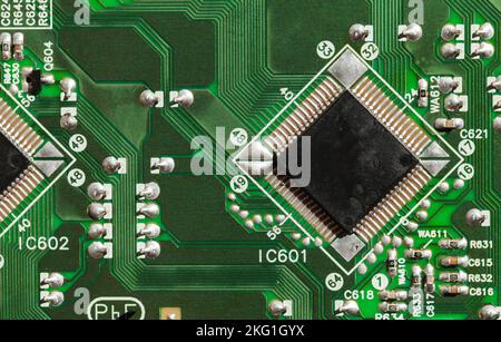 Microchip und Kondensatoren befinden sich auf einem grünen gedruckten Schaltkreis, Draufsicht, Nahaufnahme Stockfoto