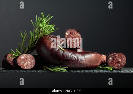 Spanischer Blutwurst oder Blutwurst mit Rosmarin auf schwarzem Hintergrund. Stockfoto