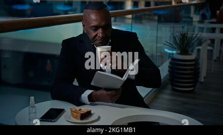 Afrikanischer Mann Arbeiter Geschäftsmann Arbeitgeber Unternehmer sitzen am Tisch in Café Cafeteria Restaurant aromatischen Kaffee trinken Tee Latte Cappuccino Stockfoto