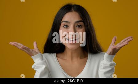 Nahaufnahme Porträt im Studio gelb Hintergrund indische ethnische Frau Mädchen Dame weiblich Blick auf die Kamera mit großen Augen offenen Mund sagen wow Sieg Stockfoto