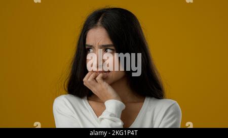 Weibliche Porträt isoliert traurig Angst besorgt indischen ethnischen Frau Dame Mädchen im Studio gelb Hintergrund nervös Gefühl Panik beißen Nägel ängstlich Stockfoto