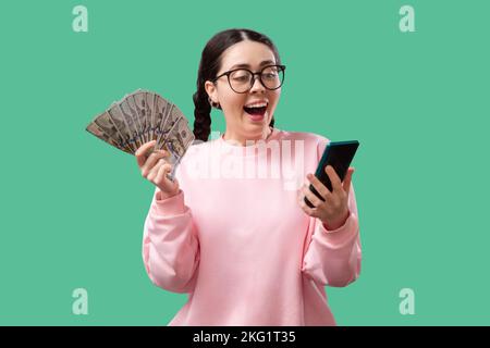 Porträt einer fröhlichen jungen Frau, die Geldscheine hält und isoliert auf gelbem Hintergrund feiert Stockfoto