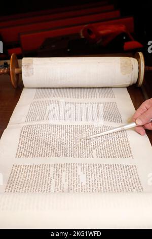 Rabbin hält einen yad in der Hand und liest eine uralte Tora-Schriftrolle. Yom Kippur. Stockfoto