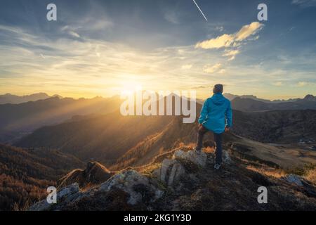 Mann auf Stein auf dem Hügel und wunderschöne Berge im Dunst Stockfoto