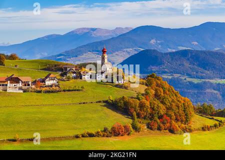 Herbst mit Herbstfarben in den Dolomiten, in Südtirol, mit Blick auf das Dorf Mittelberg mit der Nikolaikirche. Mittelberg liegt Stockfoto