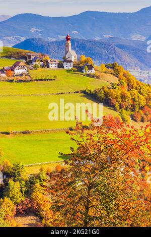 Herbst mit Herbstfarben in den Dolomiten, in Südtirol, mit Blick auf das Dorf Mittelberg mit der Nikolaikirche. Mittelberg liegt Stockfoto