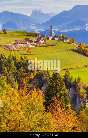 Herbst mit Herbstfarben in den Dolomiten, in Südtirol, mit Blick auf das Dorf Mittelberg mit der Nikolaikirche. Mittelberg liegt Stockfoto